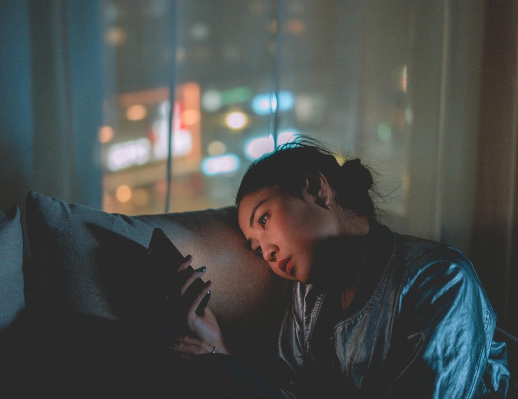 Young girl looking at her cellphone in a dark room