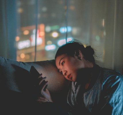 Young girl looking at her cellphone in a dark room